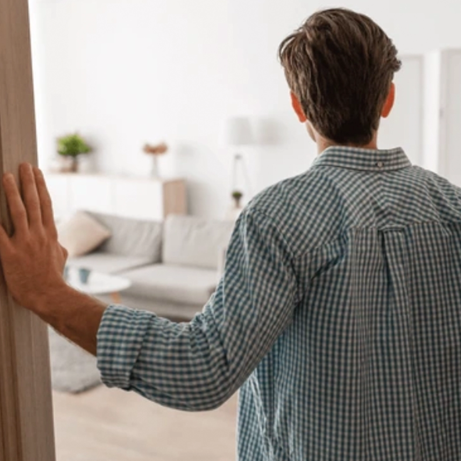 Man standing in the doorway to his apartment with his back to the camera